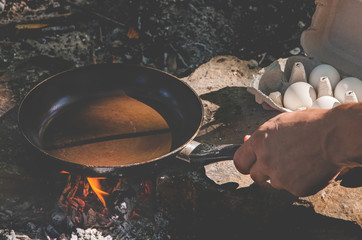 Men's hands prepare breakfast in a hike on a fire