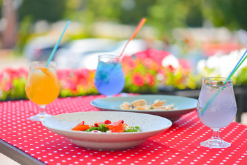 Served table at summer terrace cafe. Salmon salad, pasta with clams and three fruit alcohol cocktails.