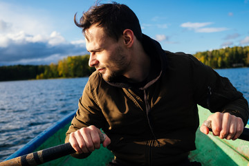 A man rowing on oars on an autumn lake