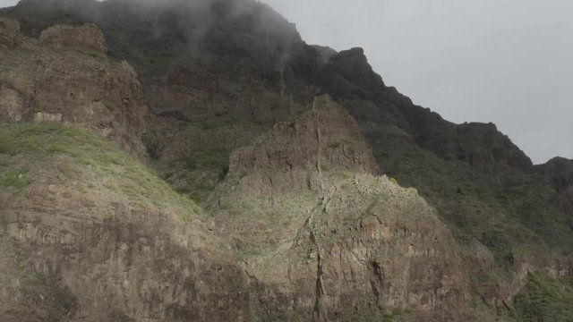 Impressive volcanic rock face with sunstripe and misty clouds forming.  Masca, Tenerife.
