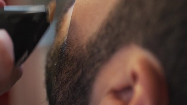 Barber/Hairdresser trim beard with trimmer. Shot on very closeup. Slowmotion at 50%