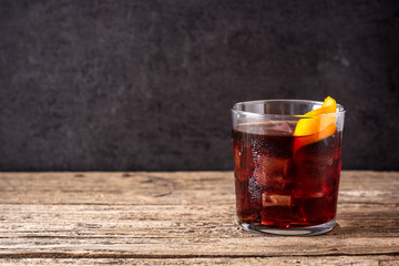 Boulevardier cocktail and orange zest on wooden table. Copy space	