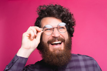 Close up portrait of smiling bearded hipster man touching eyeglasses.