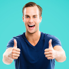 Portrait of happy smiling cheerful man, showing thumb up gesture, against aqua marine blue color background. Male caucasian model at studio. Square composition.