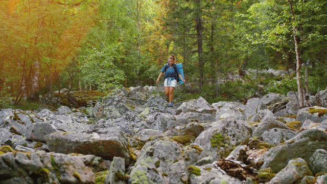 Woman with backpack hiking on rocks, trekking on stones, difficult hiking