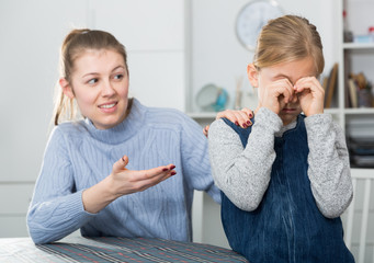 Mother comforts offended little daughter at home. High quality photo