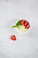Homemade avocado panna cotta with strawberries, mint in a white bowl. Sugar, lactose, gluten free....