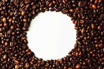 Coffee beans are scattered over the surface on a blank white background. a handful of brown coffee beans. Coffee background with copy space for an inscription, text or round logo. Mock up.