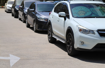 Closeup of front side of white car with  other cars parking in outdoor parking area in sunny day. 