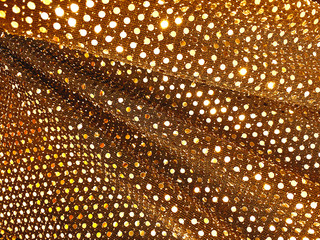 Golden sequins background - abstract festive backdrop for Holiday and party banner. Glamour shiny background with sequin texture and blinking lights. Shimmering fabric sequins in gold color