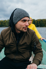 A woman and a man sail on a boat on an autumn lake