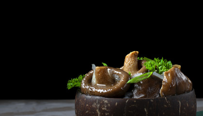 Pickled milk mushrooms with onion and spices topped with parsley in wooden bowl. Russian cuisine appetizer. Copy space