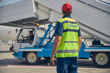 Man in a reflective vest looking at a vehicle operator