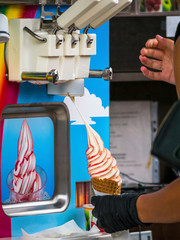 Close up with female hands filling a cone with ice cream from the ice cream machine.