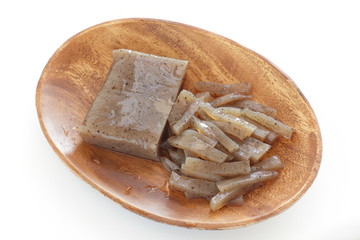 Chopped konnyaku on wooden plate on white background