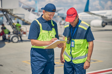 Two smiling men standing at the airdrome