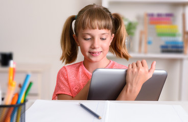 Girl studying at home taking distance lessons using digital tablet