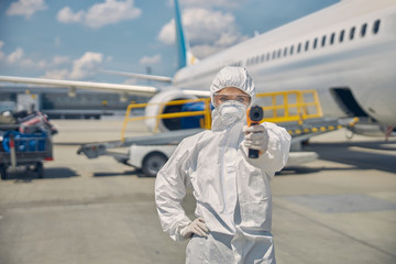 Woman in sterile gloves taking passenger temperature