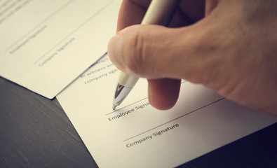 Hand of a man signing a document. Hand holding a pen and signing a Employment Contract. Vintage...