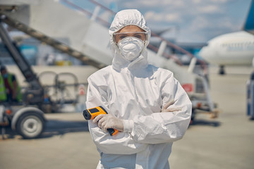 Woman with an infrared thermometer looking at the camera