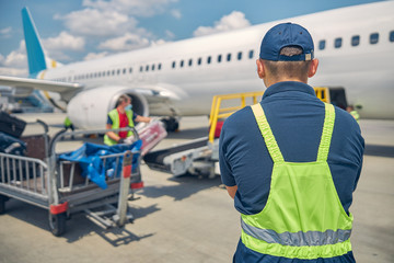 Baggage handlers loading suitcases onto an airplane