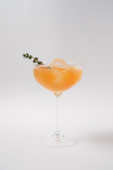 Cocktail with ice crust and orange liqueur in a tall glass, decorated with rosemary.