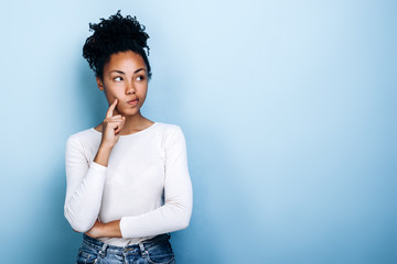 Pensive girl standing in the studio on a background of blue wall