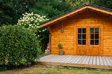 Fototapeta na wymiar Orange wooden garden shed and a large white hydrangea next to it