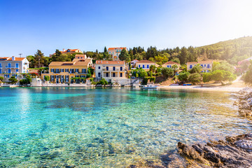 Blick auf das idyllische Dorf Fiskardo auf der ionischen Insel Kefalonia, Griechenland, mit klarem, türkisem Meer - obrazy, fototapety, plakaty
