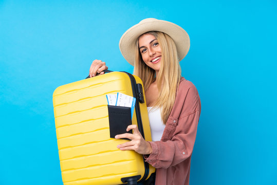 Young Uruguayan woman over isolated blue background in vacation with suitcase and passport
