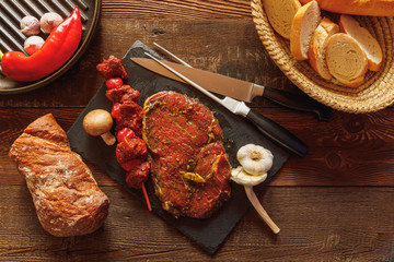 bbq skewer of beef and tomato spiced slice of meat on slate plate with garlic and mushroom bread in basket chilli pepper and cast-iron grill pan