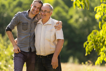 Portrait of a smiling father with adult son at the park