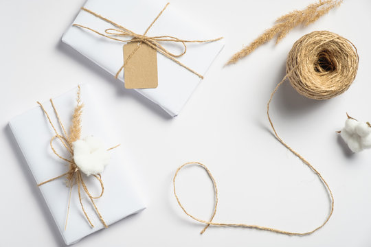 Handmade Christmas presents and string rope on white background. Christmas, winter holidays, New year preparations concept. Flat lay style, top view