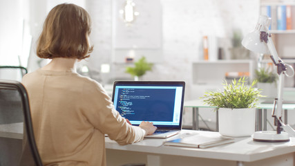 Young Creative Woman Software Developer Writes Code on Her Laptop Computer. She Sits in Her Bright Modern Developers Office.
