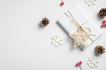 Christmas handmade gift box wrapped eco-friendly packaging paper, star, pine cone, wooden snowflakes on white table. Winter holidays, Christmas, New Year concept.