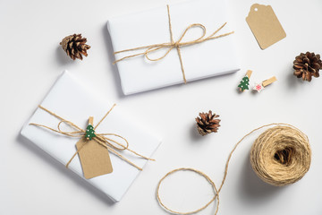 Obraz na płótnie Canvas Christmas background with gift boxes, string rope, pine cones on white. Preparation for holidays. Eco friendly Christmas presents, zero waste concept.