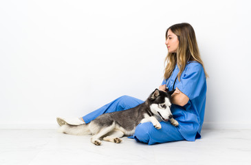 Veterinary doctor with Siberian Husky dog sitting on the floor looking side