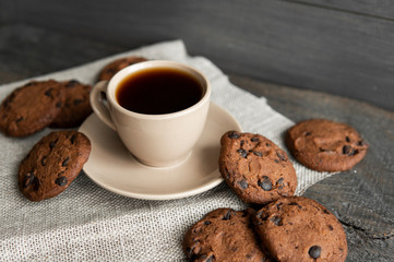 Coffee cup with cookies on wooden table background. Mug of black coffee with chocolate cookies. Fresh coffee beans.