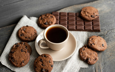Coffee cup with cookies and chocolate on wooden table background. Mug of black coffee with chocolate cookies. Fresh coffee beans.