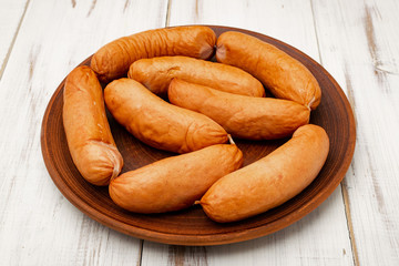 sausages on a plate on a white wooden background.