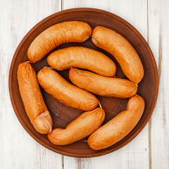 sausages on a plate on a white wooden background.