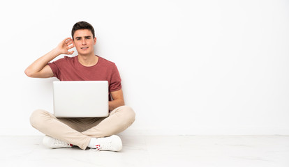 Teenager man sitting on the flor with his laptop having doubts