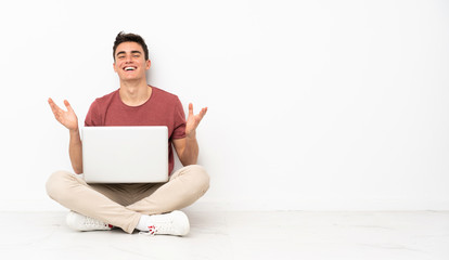 Teenager man sitting on the flor with his laptop smiling a lot