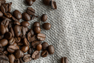 Coffee beans on a linen textile and on a wooden table background. Fresh arabica coffee beans.