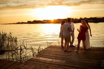 Group of friends enjoying the sunset on the lake