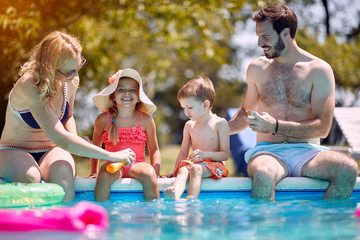 Sun protection - Family put suncream on little children before swimming.