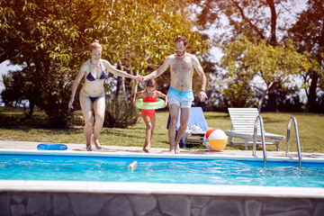 Fototapeta na wymiar Family having fun and relaxing in outdoor swimming pool