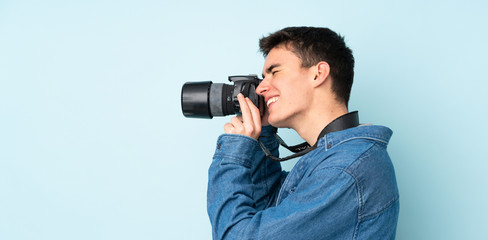 Teenager photographer man isolated on blue background