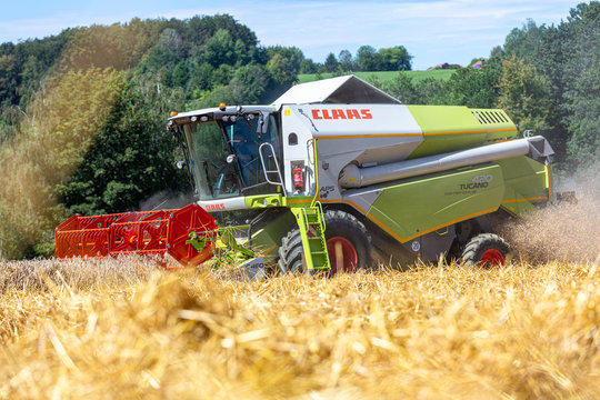 BAVARIA / GERMANY - AUGUST 20, 2020: Claas Tucano 420 combine harvester threshes grain in an agriculture field.