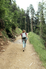 Obraz premium Woman with backpack view from the back. Person on a hike in the vicinity in summer. Digital detox and rejuvenation in the forest in the mountains.
